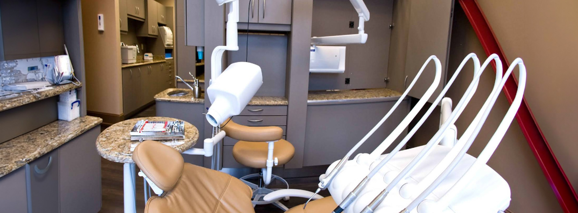 The image shows a dental office interior with various pieces of equipment and furniture, including chairs, cabinets, and a countertop.