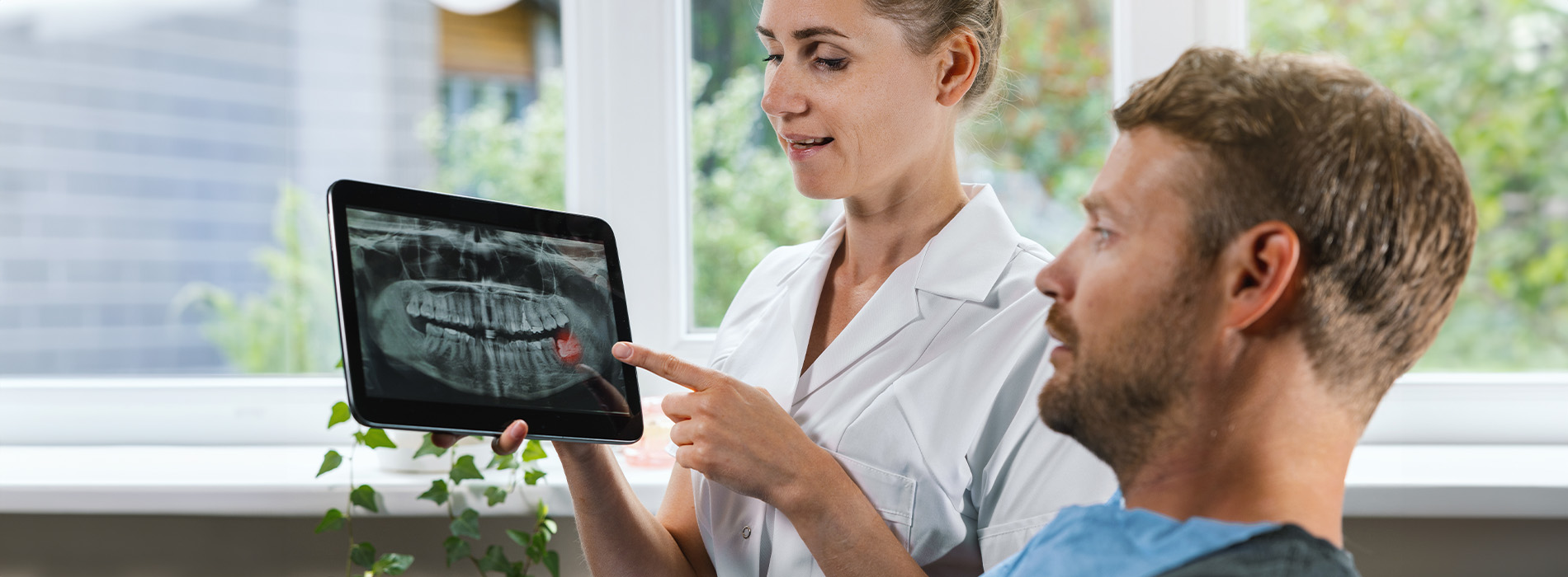 A man and woman looking at a tablet screen with an X-ray displayed, suggesting medical consultation or diagnosis.