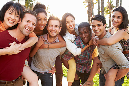 The image shows a group of people posing together outdoors during daylight with smiles on their faces.